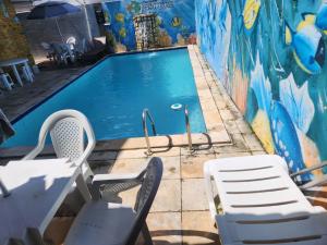 a swimming pool with two chairs and a mural at Pousada Jasmine in João Pessoa