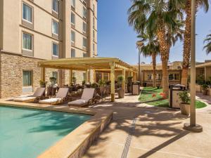 een hotel met een zwembad met stoelen en een prieel bij Hotel Mesaluna Near American Consulate in Ciudad Juárez