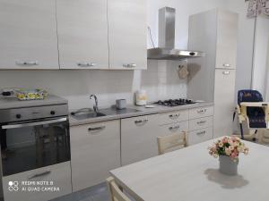 a kitchen with white cabinets and a sink and a table at casa Palmira in Orvieto