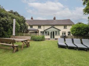 einen Picknicktisch und Stühle im Hof eines Hauses in der Unterkunft 2 Pigsfoot Cottages in Tiverton