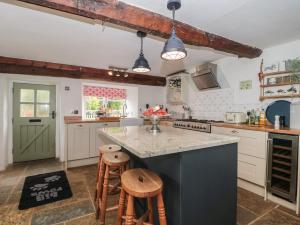 eine Küche mit weißen Schränken und einer Theke mit Stühlen in der Unterkunft 2 Pigsfoot Cottages in Tiverton