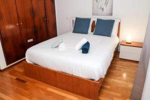 um quarto com uma grande cama branca com almofadas azuis em Nazaré Landscape em Nazaré