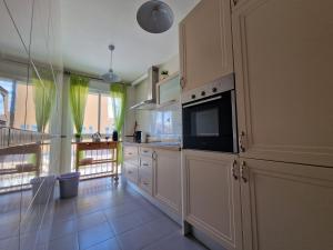 cocina con armarios blancos y microondas negro en Apartamento La vida en Málaga