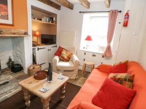 a living room with an orange couch and a table at Middlehope Cottage in Bishop Auckland