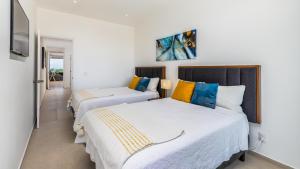 2 camas en una habitación con paredes blancas en Brand New Condo Aria Ocean 501 by Kivoya, en Nuevo Vallarta 