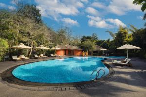 a pool at a resort with chairs and umbrellas at Taj Corbett Resort and Spa Uttarakhand in Rāmnagar