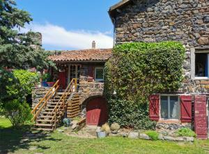 una casa de piedra con una puerta roja y hiedra en Les gîtes Estaou Treillo, en Le Monastier sur Gazeille