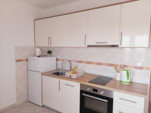 a white kitchen with a sink and a refrigerator at Apartments Donadic II, Caska in Novalja
