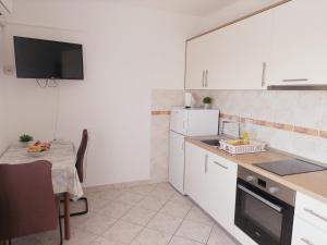 a kitchen with white cabinets and a small table with a tableablish at Apartments Donadic II, Caska in Novalja