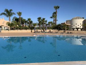 a large swimming pool with palm trees and a building at Casa Saudade - Luxury penthouse apartment with stunning views in Estômbar +28 photos