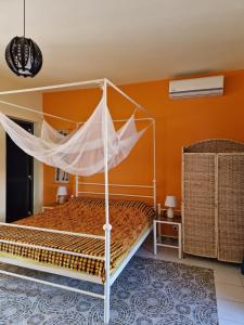 a bedroom with a bed with a mosquito net at DEKK JAMM, où l'on trouve la paix in Toubab Dialaw