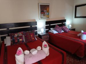 a bedroom with two beds with red sheets and towels at HOSTAL LA PAZ in Antigua Guatemala