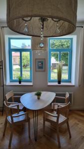 uma sala de jantar com uma mesa e cadeiras e duas janelas em 5 stylových apartmánů v srdci Jeseníků em Loučná nad Desnou