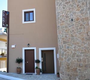 a building with two doors and a stone wall at Alkioni's Nest Apartments in Arkoudi