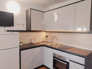 a kitchen with white cabinets and a sink at Apartments Donadic I, Caska in Novalja