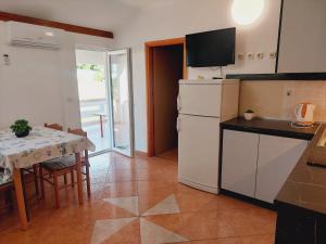 a kitchen with a table and a white refrigerator at Apartments Donadic I, Caska in Novalja