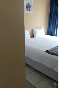 a bedroom with a bed with white sheets and pillows at Ross Height Unit 16 in Richards Bay