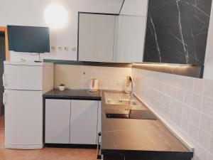 a kitchen with white appliances and a black counter top at Apartments Donadic I, Caska in Novalja