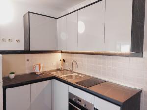 a kitchen with white cabinets and a sink at Apartments Donadic I, Caska in Novalja