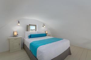 a white bedroom with a large bed with a mirror at En Plo Boutique Suites in Oia