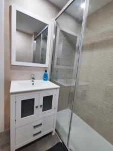 Un baño con lavabo blanco y ducha. en Apartamentos BENALBEACH, en Benalmádena