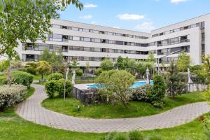 an apartment building with a garden in front of a building at Atria Urban Gateway, 2BR Condo + Pool in Bucharest
