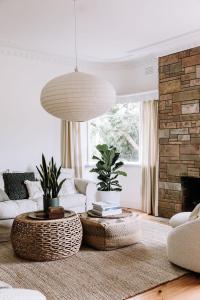 a living room with white furniture and a brick fireplace at Miss Boulevard - Stylish Art Deco Villa in Shepparton