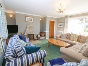 a living room with couches and a table and a tv at Llwyn Celyn in Pwllheli
