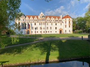 un gran edificio blanco con un frondoso patio verde en Ferienwohnung am Südwall All INCLUSIVE en Celle