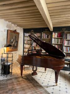 um piano numa sala com uma biblioteca com livros em La Maison de Fabienne em Tarascon