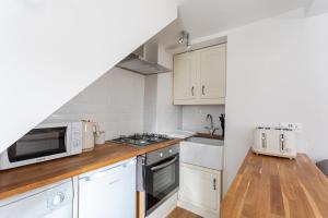 a kitchen with white cabinets and a microwave at Cobble Cottage in Richmond