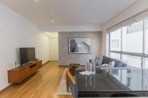 Una sala de estar con un sofá y un televisor. en Stylish 2BR in Miraflores, en Lima