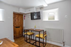 a room with a table and a tv on the wall at Cobble Cottage in Richmond