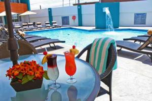una mesa con dos cócteles junto a la piscina en Baja Inn Hoteles Ensenada en Ensenada