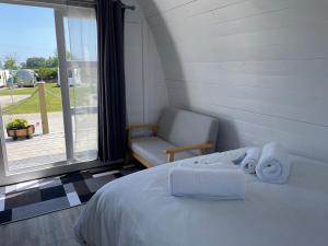 a bedroom with a bed and a chair and a window at Cosy Glamping Pod with shared facilities, Nr Kingsbridge and Salcombe in Kingsbridge