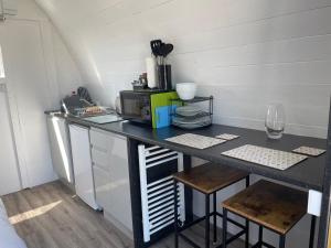 a kitchen with a black counter with a microwave at Cosy Glamping Pod with shared facilities, Nr Kingsbridge and Salcombe in Kingsbridge