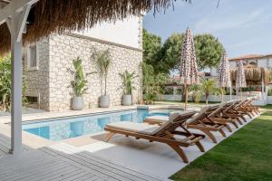 a group of lounge chairs next to a swimming pool at Sandal Alaçatı - Adult Only in Alacati