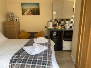 1 dormitorio con 1 cama con toallas en Auntie Bett's - Cosy double ensuite room with mini kitchen en Kingsbridge