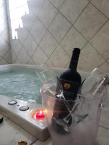 a bottle of wine in a bath tub with a glass at Pousada Jasmine in João Pessoa