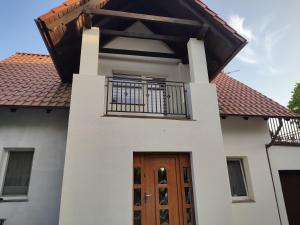 Cette maison dispose d'une porte en bois et d'un balcon. dans l'établissement Berneński Zakątek, à Charzykowy