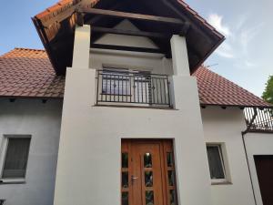 a house with a wooden door and a balcony at Berneński Zakątek in Charzykowy