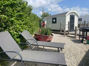 a patio with two benches and a trailer at Estuary View - Cosy Shepherds Hut in Kingsbridge