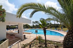 einen Pool mit einer Palme neben einem Gebäude in der Unterkunft Moradia V 60 in Quinta do Lago