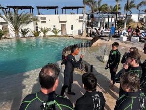 a man in a wetsuit standing next to a swimming pool at Ventana Blue Hotel in El Sargento