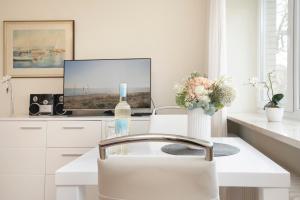 eine weiße Küche mit einem TV und einem Tisch mit einer Flasche Wein in der Unterkunft Haus Seepferdchen am Meer Appartement 2 in Timmendorfer Strand