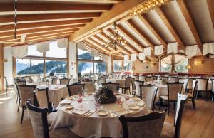 ein Esszimmer mit Tischen, Stühlen und Fenstern in der Unterkunft Cristal Palace Hotel in Madonna di Campiglio