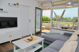 Una sala de estar con un sofá, un televisor y una mesa. en Kaiserhof App 213 inkl WLAN, en Grömitz