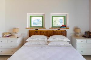 a bedroom with a white bed with two windows at Villa meraviglia in Collazzone