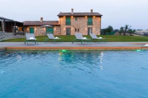 a pool with chairs and a house in the background at Villa meraviglia in Collazzone