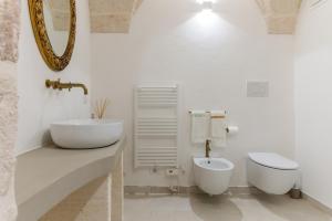 La salle de bains blanche est pourvue d'un lavabo et de toilettes. dans l'établissement Suite L' Alcova, à Fasano